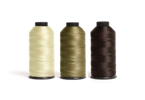 Drie spoelen hairtalk® Nylondraad in lichtgeel, blond en donkerbruin zijn netjes op een rij gerangschikt op een ongerepte witte achtergrond. Ideaal voor naadloze haarextensie-applicaties.
